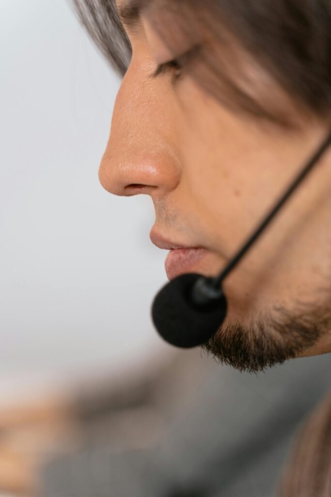 Side profile of a young male call center worker with a microphone headset, focused on work.